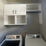 Newly installed white cabinets in laundry room over washer and dryer