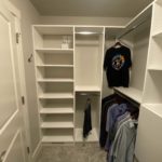 Custom white walk-in closet with mens clothing on the rod