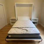 White murphy bed storage unit open with bed down in a bedroom