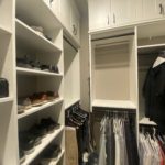 Custom height walk-in closet shelves and cabinets with clothing and shoes