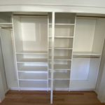 Newly installed white hallway closet shelves, coat hangers and drawers