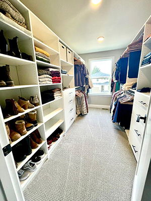 long and narrow walk in closet full of clothes and items demonstrates vast storage potential with custom features