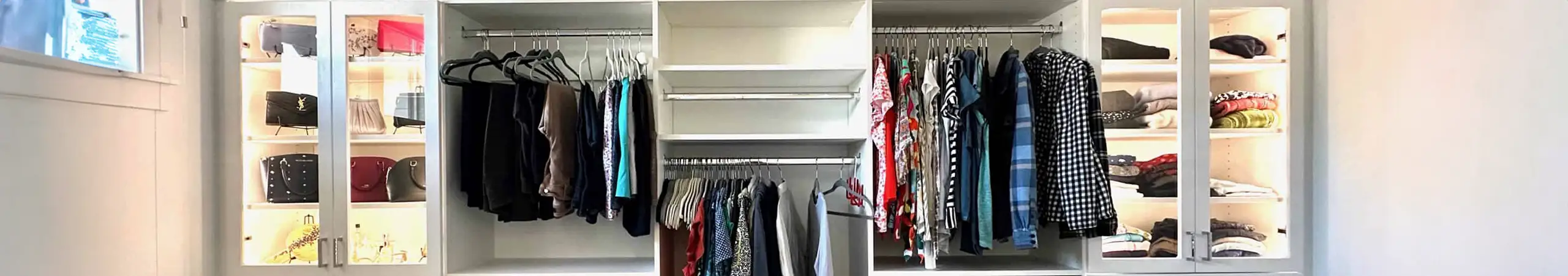 Custom walk-in closet with hanging space, shelving, and glass-front display cabinets