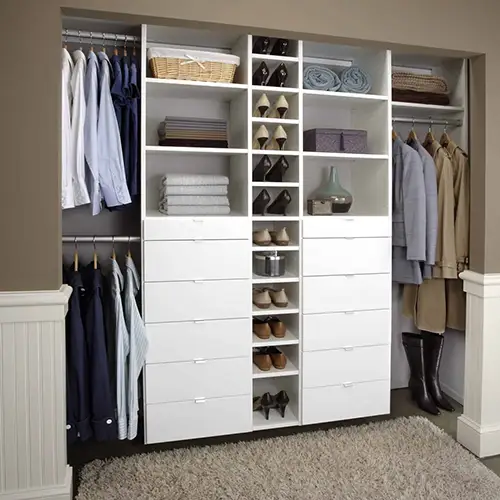 Custom reach-in closet system with hanging rods, drawers, and shoe shelving